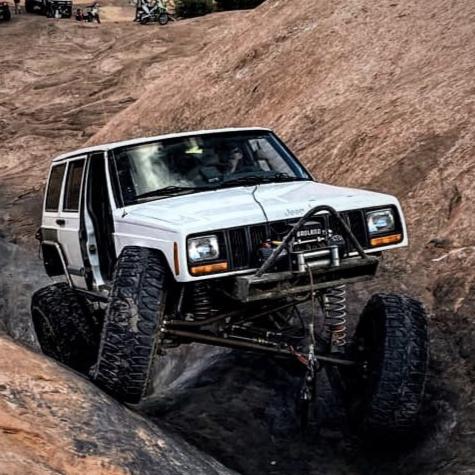Modified Jeep Cherokee XJ with long-arm suspension, high clearance steering, and coilovers crawling Moab slickrock – built with BKFabworks components