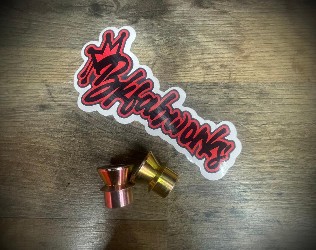 Set of 3/4 inch to 1/2 inch high misalignment spacers in gold and red zinc finish next to BKFabworks logo sticker on wood surface.
