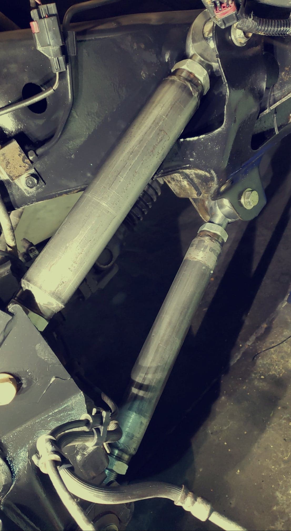 Close-up view of BKFabworks adjustable lower control arms installed on Jeep suspension with heim joints
