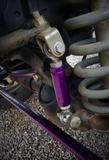 Detailed view of heavy-duty purple sway bar end link installed on Dodge Ram suspension coil spring setup from BKFabworks