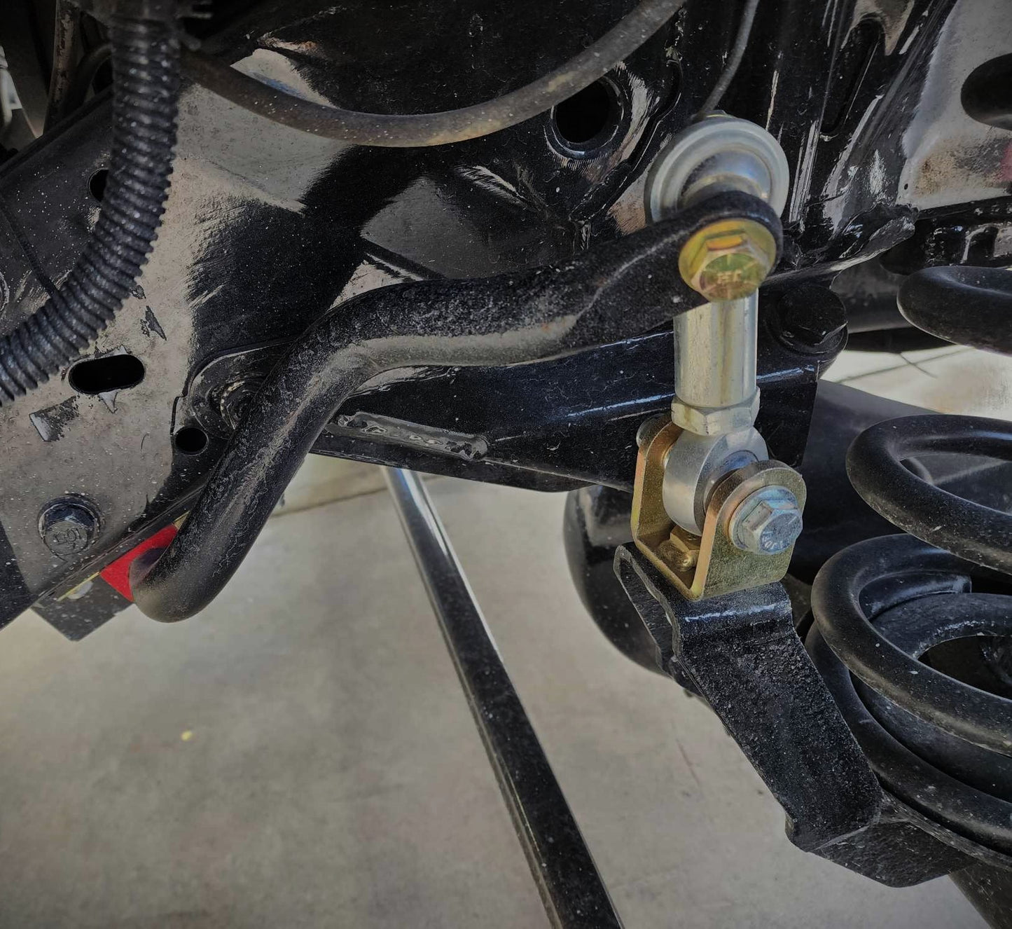 Front view of BKFabworks sway bar end link installed on 1994–2002 Dodge Ram 2500 4x4, showing heim joint connection to sway bar and control arm