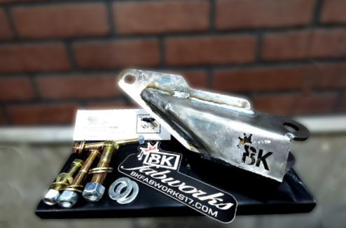 BKFabworks Dodge track bar bracket kit with mounting bolts, hardware, and raw steel bracket on display with company branding