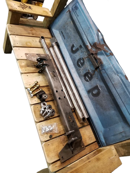 BKFabworks Jeep XJ/MJ 3-link suspension kit with unibody crossmember, link bars, heims, and hardware displayed on wood bench with Jeep tailgate backrest